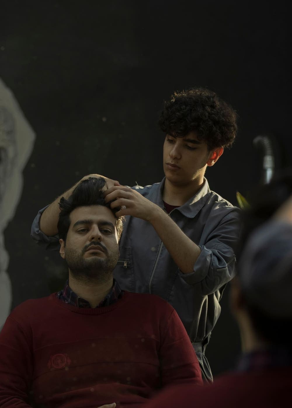 Barber styling a client’s hair in a moody studio