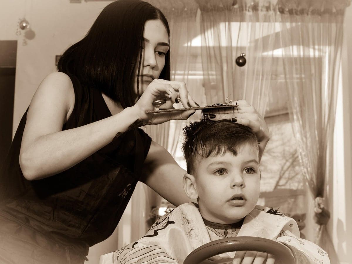 Stylist giving a young child a haircut in a children’s barber chair